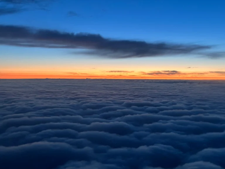 Breathtaking sunset over a sea of clouds with vibrant orange and deep blue sky creating a mesmerizing view above the horizon.